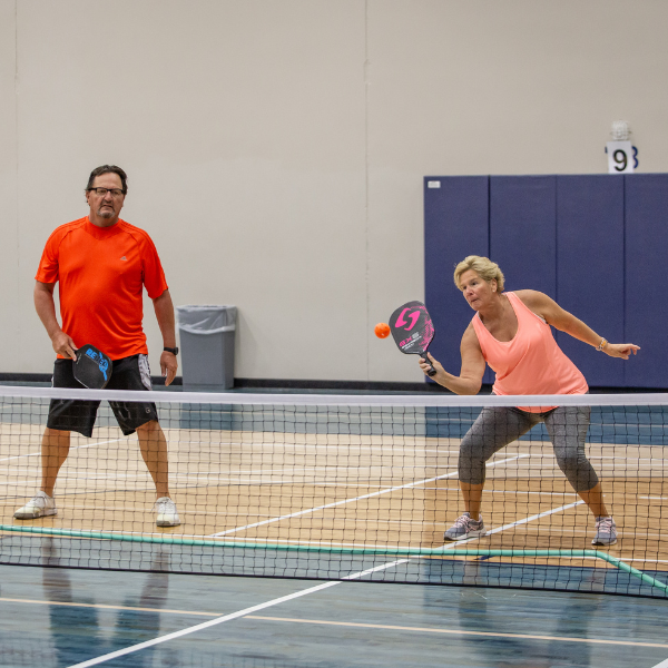 Pickleball players hitting a ball over the net